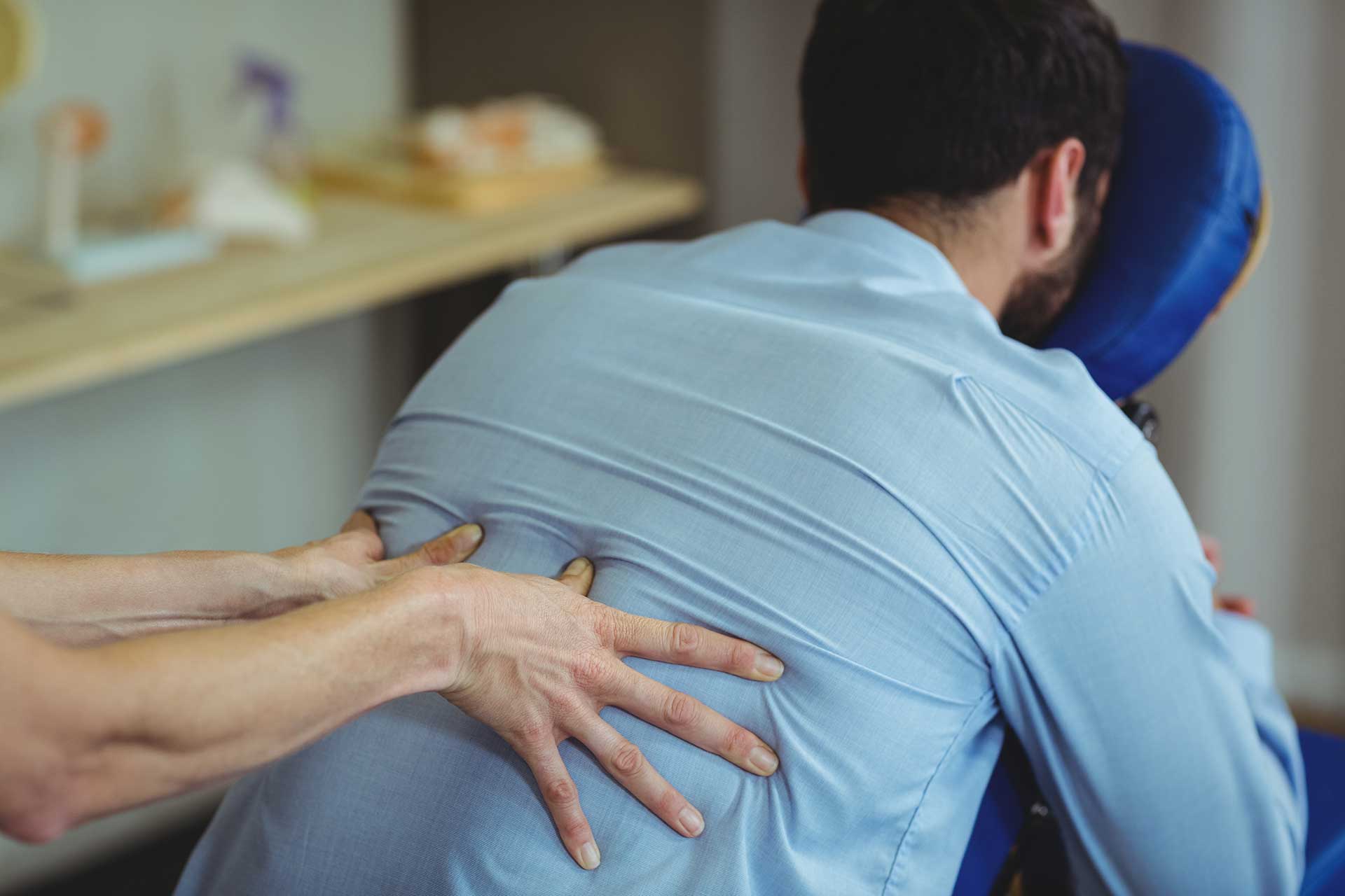 Man receiving chair massage therapy at a HealthFairsDirect.com wellness event, supporting relaxation and employee well-being.